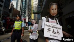 Seorang demonstran pro-demokrasi (kanan) memakai masker tahanan politik China Xu Zhiyong, yang dituduh melanggar ketertiban umum, dalam sebuah protes di Hong Kong. (Foto: Dok)
