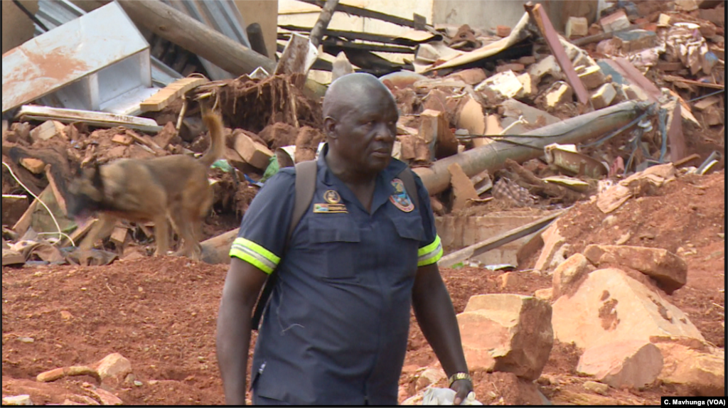 A South African police officer guides his sniffer dog in Ngangu, one of the areas hardest hit by Cyclone Idai in Chimanimani district, Zimbabwe, March 28, 2019.