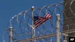 FILE - A U.S. flag flies inside the razor wire fence of the Camp VI detention facility in Guantanamo Bay Naval Base, Cuba, April 17, 2019. 