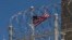 FILE - In this April 17, 2019, photo reviewed by U.S. military officials, a U.S. flag flies behind a razor wire fence of the Camp VI detention facility at Guantanamo Bay Naval Base, Cuba. 