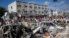 People walk amidst destruction at the scene of a double car bombing at a busy intersection, a day after the attack, in Mogadishu, Somalia, Oct. 30, 2022.