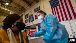 ស្ត្រី​ម្នាក់​កំពុង​ទទួល​វ៉ាក់សាំង​បង្ការ​ជំងឺ​កូវីដ១៩ នៅ​ក្នុង​សាលារៀន​មួយ ក្នុង​ក្រុង Central Falls រដ្ឋ Rhode Island ថ្ងៃទី១៣ ខែកុម្ភៈ ឆ្នាំ២០២១។​