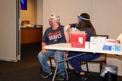 Lucinda Shelton of Acworth, Georgia, receives her covid vaccination administered by a worker from Emory Healthcare at the ball park prior to the game between the Atlanta Braves and the Philadelphia Phillies at Truist Park.