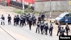 FILE - A still image taken from video shows riot police walk along a street in the English-speaking city of Buea, Cameroon, Oct. 1, 2017.