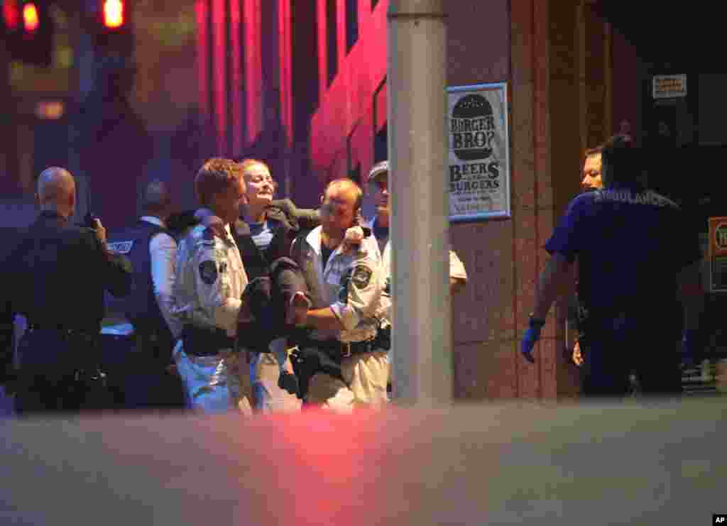A injured hostage is carried to an ambulance after shots were fired during a cafe siege at Martin Place in the central business district of Sydney, Dec. 16, 2014.