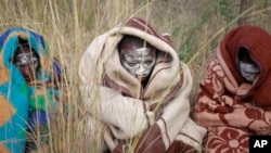 South African boys covered with a blankets and smeared with chalky mud sit in a field as they undergo a traditional male circumcision ceremony into manhood in Qunu, South Africa, June 30, 2013.
