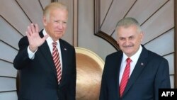 Turkish Prime Minister Binali Yildirim (R) as US Vice President Joe Biden waves as they pose for a photograph before their meeting at Cankaya Palace in Ankara, Aug. 24, 2016.