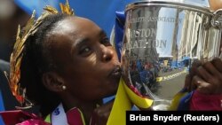 Kenya's Rita Jeptoo holds the trophy after winning the women's division at the 118th running of the Boston Marathon in Boston, Massachusetts April 21, 2014. REUTERS/Brian Snyder