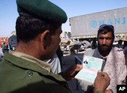FILE - A Pakistani border guard checks the passport of an Afghan national entering Pakistan through the Chaman post at Pakistan-Afghanistan border.