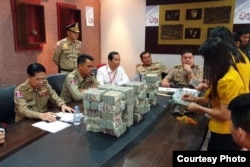 រូប​ភាព​ក្នុង​វេបសាយ​ផ្លូវការ​របស់​អង្គស្នងការស្នាន​នរបាល​ជាតិ​ចុះ​ផ្សាយ​នៅ​ថ្ងៃ​ទី​២៩ ខែ​មេសា ឆ្នាំ​២០១៩​នេះ​បង្ហាញ​ពីសាច់​ប្រាក់រឹប​អូស​បាន​ពី​ជនជាតិ​ចិន​៣​នាក់​ ដែល​ត្រូវ​បាន​អាជ្ញាធរ​កម្ពុជា​ចាប់​ខ្លួនក់ព័ន្ធ​នឹង​បទល្មើស​សម្អាត​ប្រាក់​ចំនួន​ជាង​ ៣.៥​លាន​ដុល្លារសហរដ្ឋ​អាមេរិក​ ដែល​នាំ​ចូល​ពី​ទីក្រុង​ហុងកុង​មក​កម្ពុជា។ (Courtesy Photo/Cambodia Police)