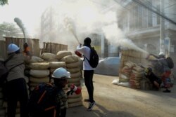 Anti-coup demonstrators sprays fire extinguishers over a barricade during a protests in Yangon, Myanmar, March 9, 2021.