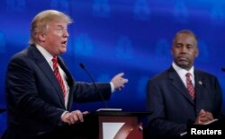 U.S. presidential candidate and businessman Donald Trump, left, speaks as Ben Carson, a retired neurosurgeon, listens at the 2016 U.S. Republican presidential candidates debate held by CNBC in Boulder, Colo., Oct. 28, 2015.