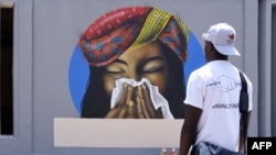 FILE - An image of a woman sneezing in a tissue serves as a reminder of preventive measure against COVID-19 at Cheikh Anta Diop University in Dakar on March 21, 2020. (Photo by Seyllou / AFP)