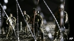 U.S. Border Patrol agents stand on the U.S. side of the border, seen through the concertina wire where the border meets the Pacific Ocean, Thursday, Nov. 15, 2018, from Tijuana, Mexico.