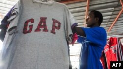 Mamadou Sarr, 23 ans, grossiste en vêtements d'occasion prépare son stand au marché de Colobane, le plus grand marché de vêtements d'occasion de la capitale sénégalaise, Dakar, le 25 juin 2019.