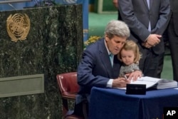 U.S. Secretary of State John Kerry holds his granddaughter as he signs the Paris Agreement on climate change at U.N. headquarters, April 22, 2016.