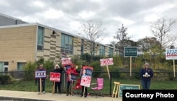 Lowell residents holding banners supporting their candidates at a polling station in Lowell, Massachusetts, November 7, 2017. (Courtesy photo of Sidney Liang)