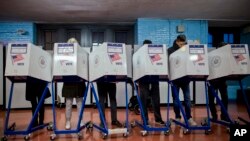 FILE - Voters fill out their forms as they prepare to vote at a polling station in the Brooklyn borough of New York, Nov. 8, 2016.