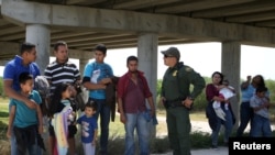 Un agent de la police des frontières s'entretient avec des migrants qui ont franchi illégalement la frontière entre le Mexique et les États-Unis, dans le secteur de Rio Grande Valley, près de McAllen, au Texas, le 2 avril 2018.