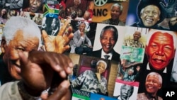 A well-wisher uses his phone to take a picture of a banner of photos of Nelson Mandela, outside the Mediclinic Heart Hospital in Pretoria, July 18, 2013.