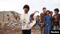 Seorang anak laki-laki tampak memegang pecahan peluru meriam dari rudal di lokasi serang yang diluncurkan oleh kelompok pemberontak Houthi di Marib, Yaman, pada 3 Oktober 2021. (Foto: Reuters/Ali Owidha)
