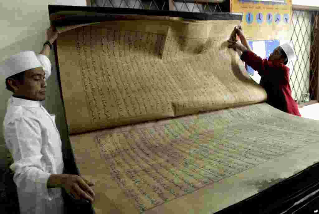 Dua orang guru menunjukkan kitab suci Al-Quran raksasa yang dipamerkan di pesantren Al-Ashriyyah Nurul Iman di Parung, Jawa Barat, Indonesia.