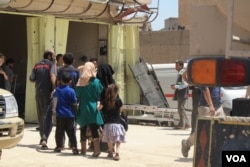 After Raqia was shot in her chest as she ran on June 4, 2017, her children and grandchildren crowd into a field clinic as she is treated in Mosul, Iraq. (H. Murdock/VOA)