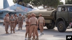 FILE - Russian air force personnel stand near a Russian war plane at Hmeymim airbase, Syria, Oct. 22, 2015.