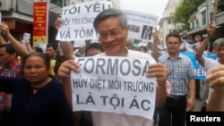 Political dissident Nguyen Quang holds a sign which reads "Formosa - damaged the environment and is a criminal" during a protest in Hanoi, Vietnam May 1, 2016 against a unit of Taiwan’s Formosa Plastics.