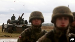 FILE - Polish soldiers prepare for an official welcoming ceremony for troops from U.S., Britain, Romanian and other nationalities, part of a NATO mission to enhance Poland's defense, in Orzysz, northeastern Poland, April 13, 2017.