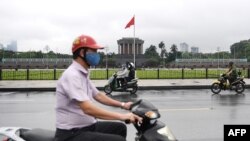 បុរស​ម្នាក់ជិះម៉ូតូ​ពាក់ម៉ាស់​ក្នុង​ទីក្រុង​ហាណូយ​កាលពី​ថ្ងៃទី​២៣ ខែមេសា ឆ្នាំ២០២០។