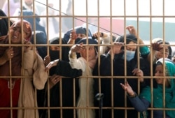 Afghan women wait to receive tokens needed to apply for a Pakistani visa, after others were killed in a stampede for the tokens in Jalalabad, Afghanistan, Oct. 21, 2020.