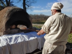 Justin Cherry bakes bread in a clay, wood-fired oven he made. He uses the same kind of wheat that was grown on Mount Vernon during Washington’s time. (Photo: Deborah Block)