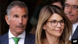 FILE - In this April 3, 2019, photo, actress Lori Loughlin, front, and her husband, clothing designer Mossimo Giannulli, left, depart federal court in Boston after a hearing in a nationwide college admissions bribery scandal.