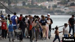 FILE - Refugees and migrants from the destroyed Moria camp wait to board a ferry that will transfer them to the mainland, at the port of Mytilene on the island of Lesbos, Greece, Sept. 28, 2020. 
