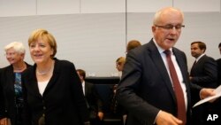 German Chancellor Angela Merkel, left, smiles as parliamentary faction leader Volker Kauder opens a meeting of the Christian Democratic Party's parliamentary faction on the eve of Wednesday's vote on another bailout package for Greece, Aug. 18, 2015.