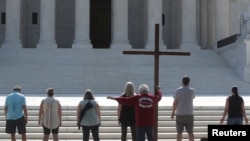 Demonstrators gather outside the U.S. Supreme Court as the court ruled that religious institutions like churches and schools are shielded from employment discrimination lawsuits in Washington, July 8, 2020. 