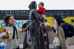 Afghan refugees board buses that will take them to a processing center after arriving at Dulles International Airport in Dulles, Virginia, on Sept. 2, 2021.