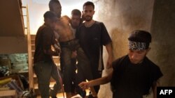 Syrian rebels carry a wounded comrade into a secret field hospital in al-Bab, northeast of Aleppo, August 10, 2012.