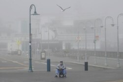 A street performer sits alone at Fisherman's Wharf in San Francisco, March 12, 2020. Gov. Gavin Newsom said sweeping guidance for Californians to avoid unnecessary gatherings to prevent the spread of coronavirus will likely extend beyond March.