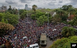A crowd of thousands of protesters demanding President Robert Mugabe stands down gather behind an army cordon on the road leading to State House in Harare, Zimbabwe Saturday, Nov. 18, 2017.
