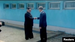 North Korean leader Kim Jong Un shakes hands with South Korean President Moon Jae-in at the concrete border as both of them arrive for the inter-Korean summit at the truce village of Panmunjom, in this still frame taken from video, South Korea April 27, 2018.