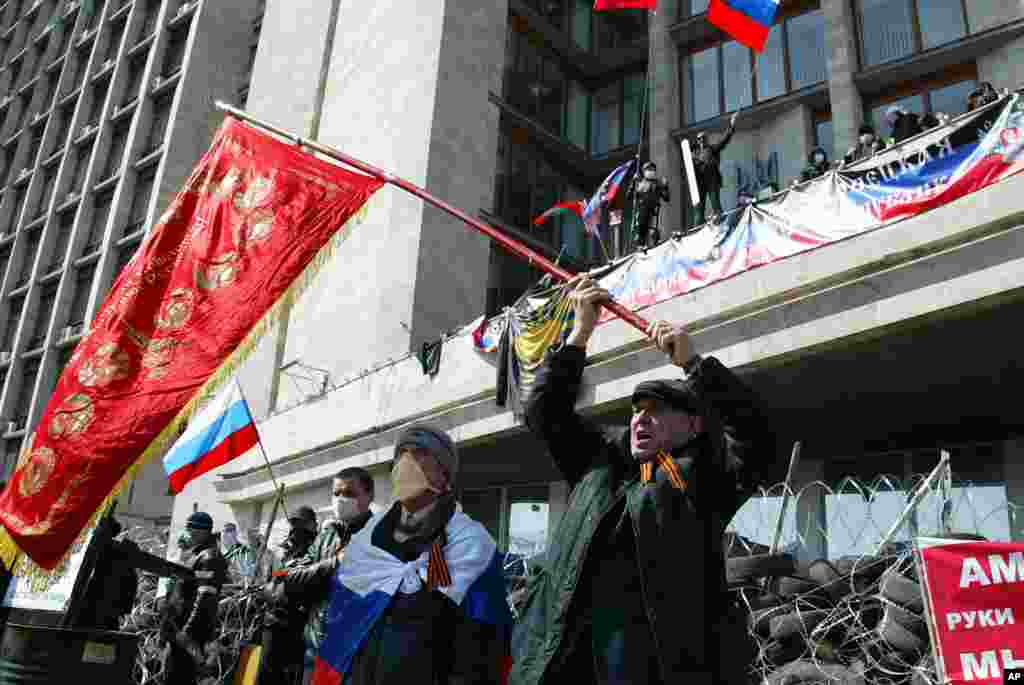 Activists wave an old Soviet and Russian national flags in front of a barricade at the regional administration building, in Donetsk, Ukraine.