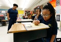 Elize'a Scott, a Key Elementary School third grade student, right, reads under the watchful eyes of teacher Crystal McKinnis, left, Thursday, April 18, 2019, in Jackson, Miss. (AP Photo/Rogelio V. Solis)