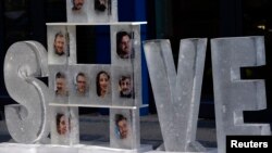 Blocks of ice with pictures of 30 people arrested in Russia for protesting Arctic oil drilling dispayed outside Gazprom offices, Berlin, Nov. 14, 2013.