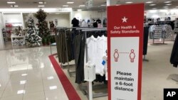 A social-distancing sign reminds shoppers to stay apart as a Christmas trees display stands at the end of walkway in a Macy's department store Thursday, Oct. 1, 2020, in northeast Denver. (AP Photo/David Zalubowski)