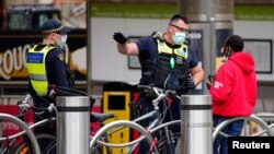 Victoria Police Protective Services Officers speak to a man on the first day of a five-day lockdown implemented in the state of Victoria in response to a coronavirus disease (COVID-19) outbreak in Melbourne, Australia, Feb. 13, 2021. 