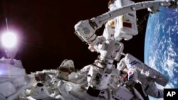 In this photo released by China's Xinhua News Agency, a screen at the Beijing Aerospace Control Center in Beijing shows Chinese astronauts Cai Xuzhe, top and Chen Dong conducting a spacewalk, around the station lab module Wentian, Saturday, Sept. 17, 2022.