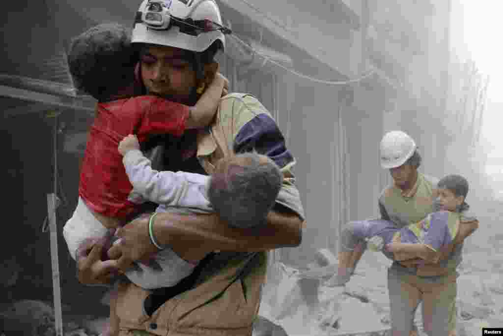 Para petugas menyelamatkan anak-anak, pasca serangan udara oleh pasukan Suriah di kota Aleppo.