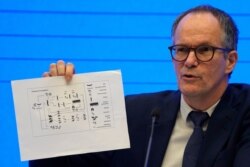 FILE - Peter Ben Embarek of the World Health Organization holds up a chart showing pathways of transmission of the virus during a press conference in Wuhan, China, Feb. 9, 2021.